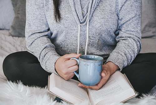 coffee cup person in gray sweater holding white ceramic mug cup